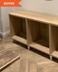 Unfinished wooden sideboard with three open compartments on a herringbone floor.