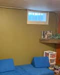 Before: Basement with green wall and broken window