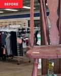 Wooden chair with a cracked seat in a thrift store, surrounded by clothing racks and decorative branches.