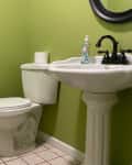 Before: a green bathroom with a white toilet and sink