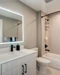 Before: a beige colored bathroom with a large rectangular mirror over the sink