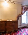 Bathroom with floral carpet, wooden vanity, green curtain, and window with pink drapes.
