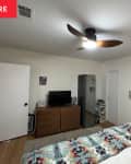 White bedroom with ceiling fan before renovation.
