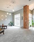 Large carpeted dining room and entryway with neutral painted walls before renovation.