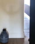 bare, white corner with dark clay pot on wood floors