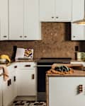 A renovated kitchen with dark countertops, white cabinets and tiled floors.