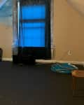 A beige attic with black carpeting.