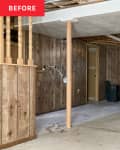 Empty wood-paneled cement-floored basement before renovation