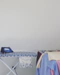 A laundry room with racks and ironing board.
