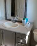 A bathroom counter with white sink and grey cabinets