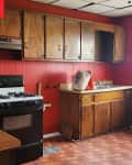 kitchen with red walls, wood cabinets, and reddish parquet flooring before renovation