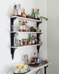 Wall-mount bar shelves made using vintage metal brackets with white quartz shelves resting on top