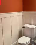 Cream wainscoting in orange painted bathroom before renovation.