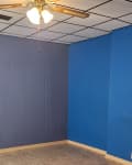 2 different shades of bue walls with paneled white ceiling and wood ceiling fan