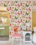 green, yellow, and red butterfly wallpaper, arched cut out to kitchen, bench floating on wall, pink vintage upholstered chair
