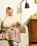 someone crocheting blanket on living room sofa
