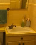 Dated tiled bathroom with vanity in right corner and toilet on left