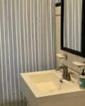 Striped shower curtain in bathroom before renovation.