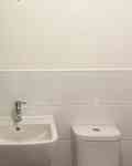 White wall behind bathroom sink and toilet before adding wallpaper.