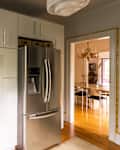 Stainless steel refrigerator in newly renovated kitchen with white cabinets.