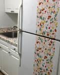 Small kitchen with white cabinets, a stainless steel sink, and a colorful terrazzo countertop and refrigerator wrap.