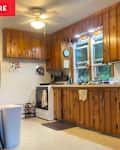 Wooden cabinets and countertops in a cozy kitchen with a white stove, clock, and various kitchen items on the counter.
