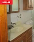 Bathroom with wooden cabinets, a beige countertop, sink, toilet, and a glass shower enclosure.