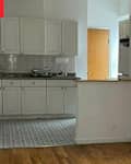 Kitchen area with white cabinets, gray countertops, and patterned tile floor, leading to a wooden door and closet.