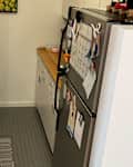 Narrow kitchen with wooden countertops, stainless steel appliances, and a small rug on tiled floor.