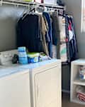 Laundry room with a washer and dryer, hanging clothes, detergent, and a storage cubby.