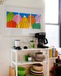 Kitchen corner with a window, colorful jello art, coffee maker, and shelves with dishes and glassware.