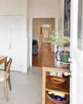Kitchen with wooden table and chairs, stainless steel fridge, stove, and a hallway leading to another room.