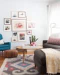 Living room with a teal armchair, gray sofa, colorful cushions, gallery wall, and patterned rug.