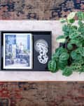 Marble coffee table with a potted plant, a book titled "Evergreen," and a decorative chain on a patterned rug.