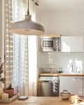 A white kitchen with butcher block counters, jars of dry pantry staples, and white backsplash