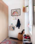 Hallway with wooden closets, colorful wall hooks, rainbow art, woven baskets, and a patterned rug.