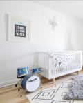 Nursery with a white crib, blue drum set, teepee, rocking chair, and striped curtains.