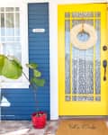 Front entrance of a blue house with white trim and a yellow door