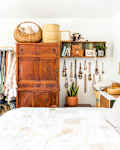 Bedroom with wooden wardrobe, open clothing rack, wall art, and decorative baskets.