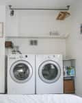 Laundry room with washer and dryer, ironing board, hangers, and cleaning supplies on shelves.