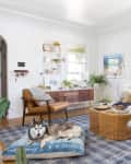Cozy living room with a husky on a blue cushion, leather chairs, a wicker coffee table, and a sofa with patterned pillows.