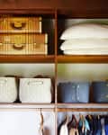 Suitcases and pillows stored on the highest shelves of a closet