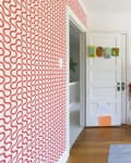 Kids' room with red patterned wallpaper, red storage shelves, toys, books, and framed art on the wall.