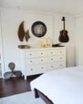 Bedroom with white dresser, wall art of an octopus, acoustic guitar, and decorative items on display.