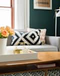 Living room with a gray sofa, geometric pillows, wooden coffee table, and vase of peach roses.