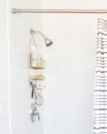 White shower with gold caddy and striped shower curtain