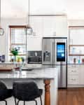 A modern white kitchen with stone countertops and stainless steel appliances