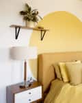 a bedroom with yellow bedding, a yellow accent wall, and a yellow circle mural painted on the white wall behind the bed