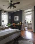 A light-filled bedroom with gray walls and hardwood flooring.