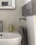 Small bathroom sink with a mirror, soap dispenser, hand soap, and towel on a ring holder.